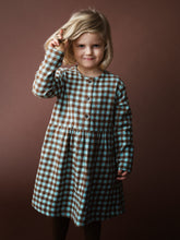 Load image into Gallery viewer, Young girl wearing a brown and green checkered dress against a brown background

