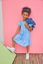 Load image into Gallery viewer, Young girl in a blue dress with a denim jacket against a pink background

