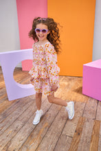 Load image into Gallery viewer, Child in a floral top and skirt wearing sunglasses posing in front of colorful geometric shapes.
