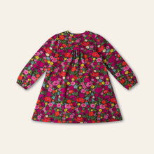 Load image into Gallery viewer, A long-sleeve children's dress with a dense, colorful floral print on a dark magenta background.
